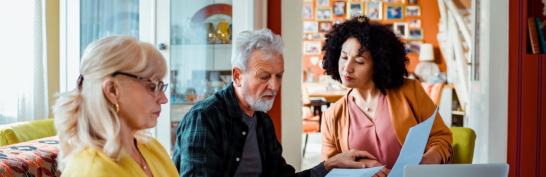Two women and a man sit at a table reviewing documents.