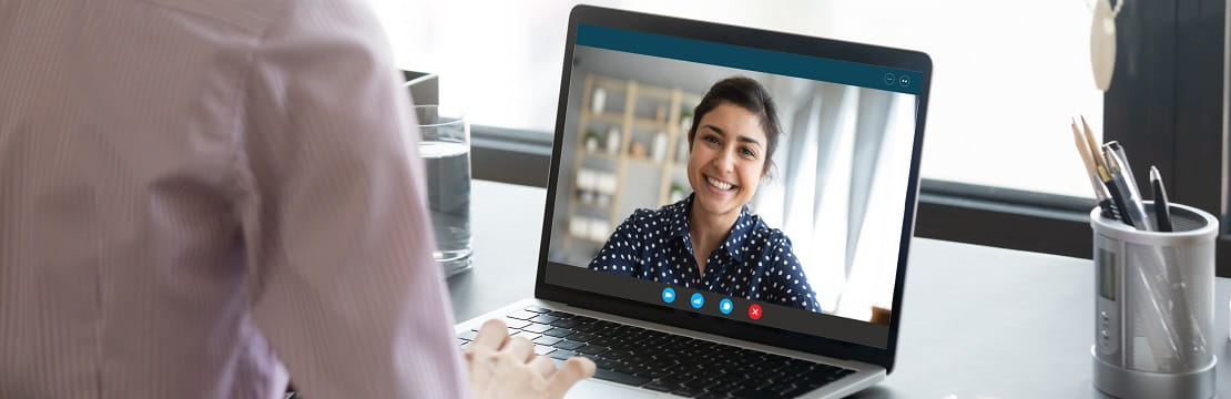 A young professional woman appears on a laptop screen as she attends a virtual meeting